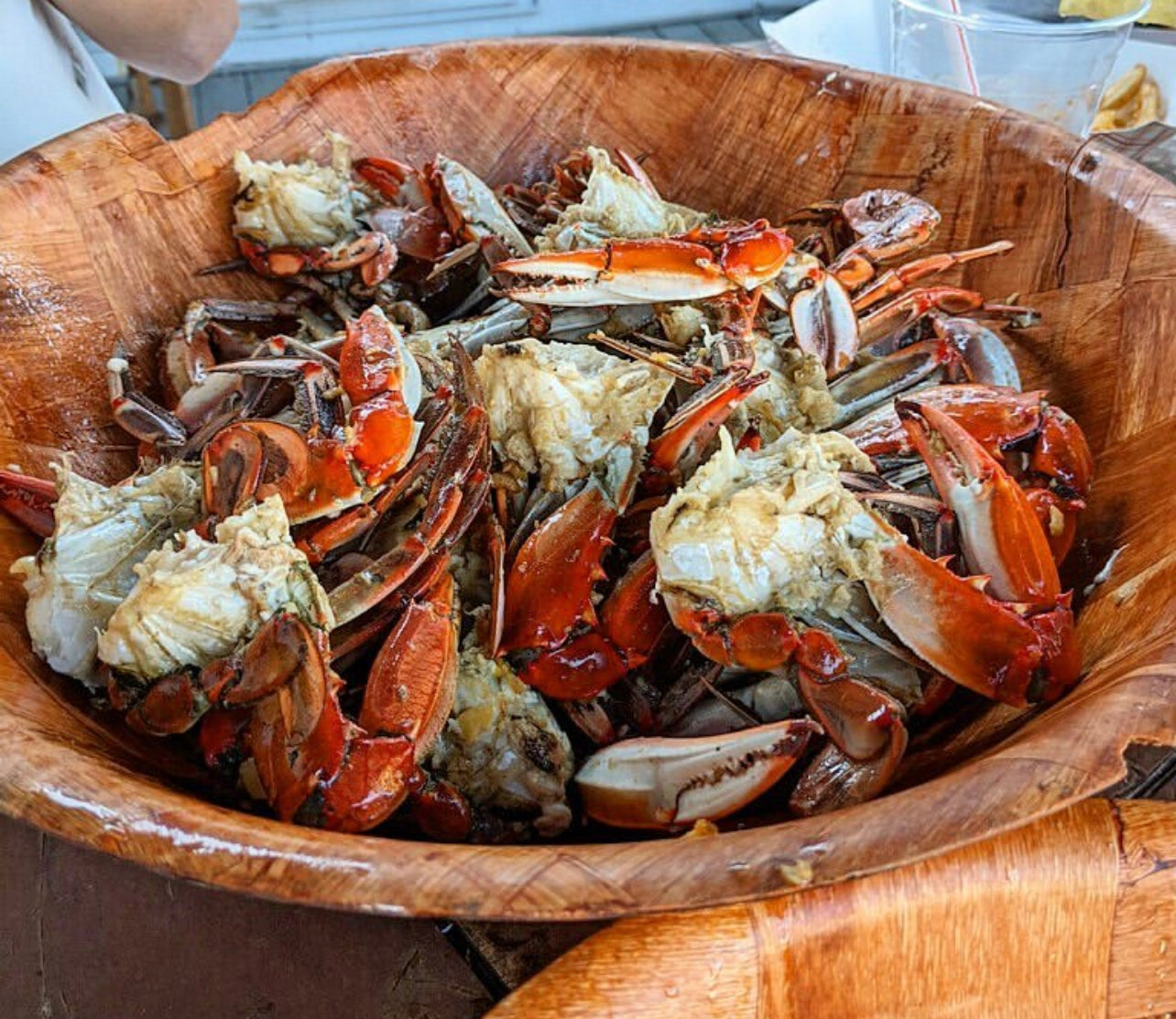 Wooden bowl filled with cooked crabs on a wooden surface